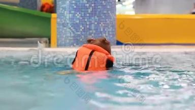穿着救生衣在游泳池里的小女孩学会游泳。 在水里游泳的婴儿